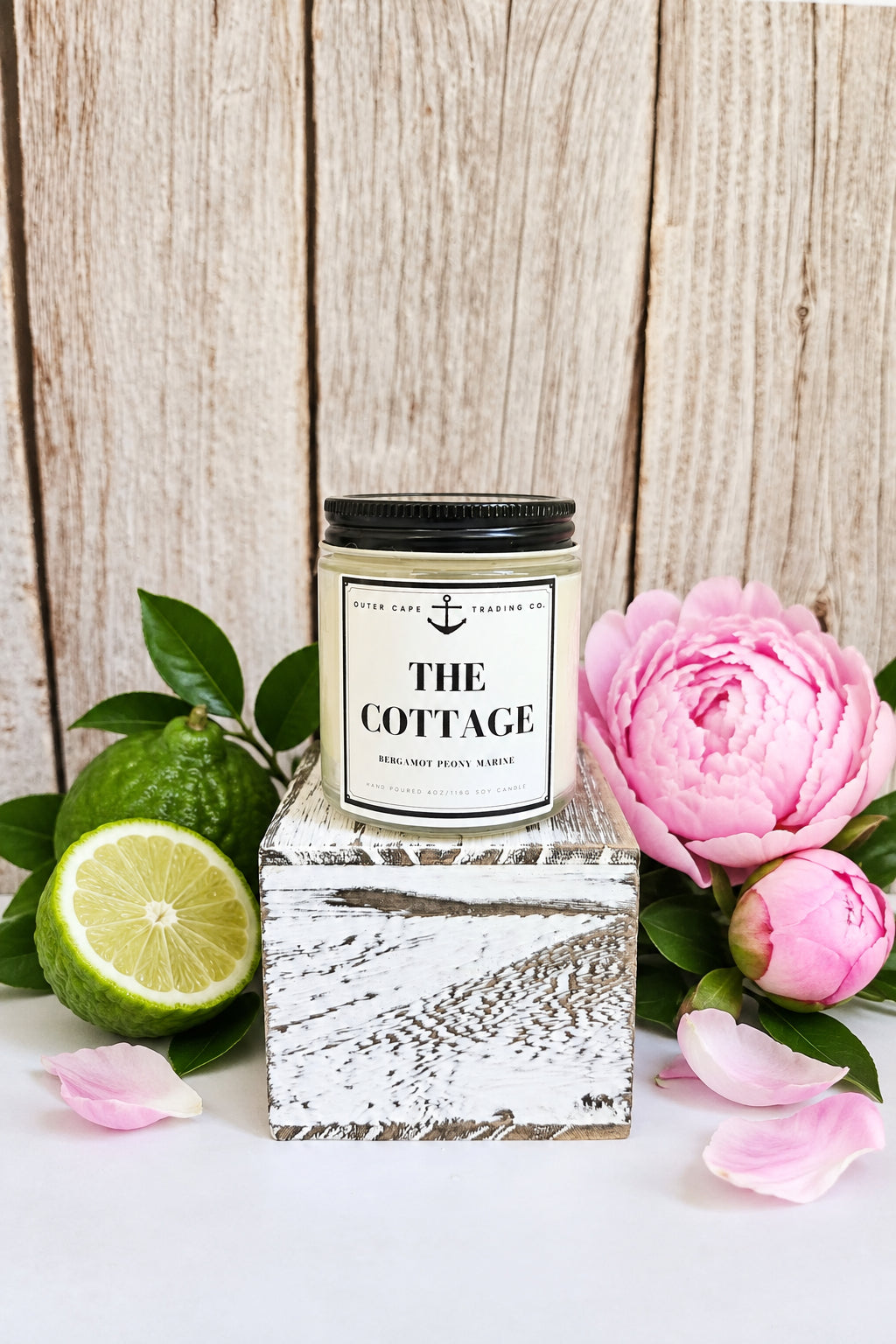 Candle labeled 'The Cottage' on a clear stand with a wooden background