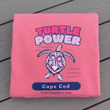 Pink hoodie featuring a sea turtle graphic, supporting Cape Cod cold-stunned turtle rescue efforts.