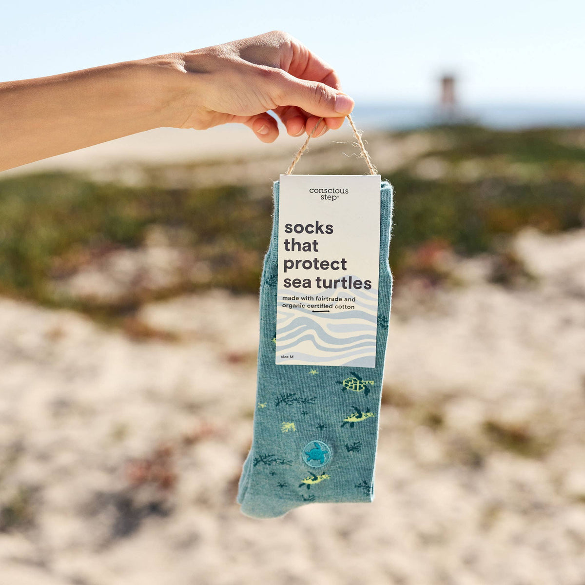 Close-up of hands holding a pair of organic cotton sea turtle protection socks to show the detailed knit pattern.