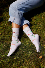 Woman wearing Surfing Pups organic cotton socks that save dogs while relaxing on green grass.
